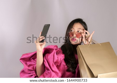 Working women wearing colorful fashion clothes, carrying shopping bags, taking a picture of herself with Christmas Phon