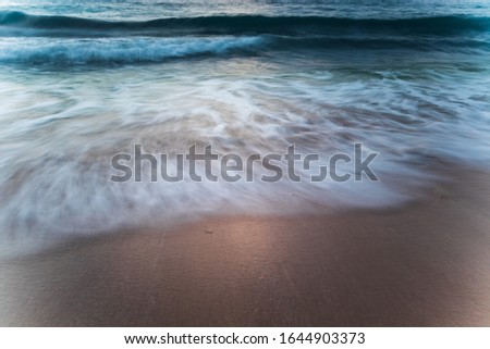 Scenic seascape. Silky milky foam waves at sandy beach. Sunset time. Waterscape for background. Slow shutter speed. Soft focus. Motion blur.  Bingin beach, Bali, Indonesia