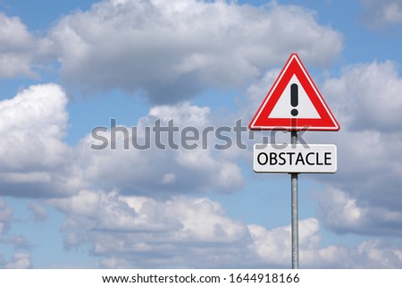 A sign with a exclamation mark warning for a dangerous situation ahead and a smaller sign below with the English word obstacle on it
