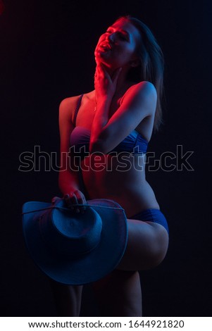 Fashionable Artistic Portrait Of A Beautiful Female Model In Bright backlit. in a wide-brimmed hat and swimsuit