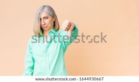 middle age cool woman feeling cross, angry, annoyed, disappointed or displeased, showing thumbs down with a serious look