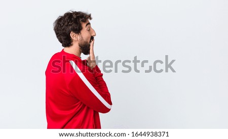 young bearded man back view yawning lazily early in the morning, waking and looking sleepy, tired and bored against copy space wall