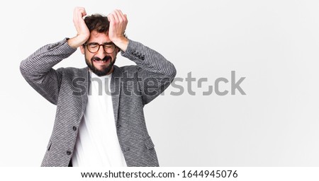 young crazy businessman feeling stressed and anxious, depressed and frustrated with a headache, raising both hands to head against flat wall