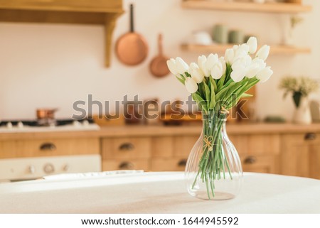 Bouquet of spring flowers in a vase on the kitchen table. Light scandinavian style. Mothers Day. March 8, International Women's Day Royalty-Free Stock Photo #1644945592