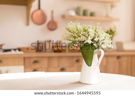 Bouquet of spring flowers in a vase on the kitchen table. Light scandinavian style. Mothers Day. March 8, International Women's Day Royalty-Free Stock Photo #1644945595
