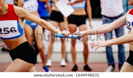 women relay team passing of baton running 4x400 meters  Royalty-Free Stock Photo #1644948631