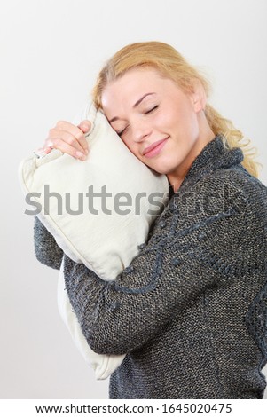 Relaxation concept. Happy sleepy woman holding and hugging cozy warm pillow preparing to sleep. Studio shot on white background