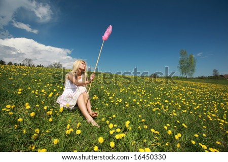 Beautiful blond girl with long hair in dandelion field