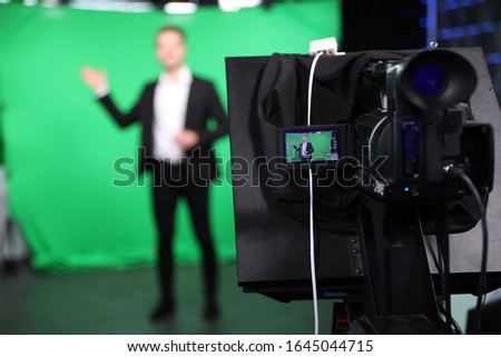 Presenter working in studio, focus on video camera screen