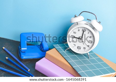 Set of school supplies and clock on table against color background