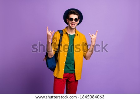 Full body photo of funky cool hipster guy traveler visit pank concert show horned symbol wear backpack vintage blue velvet headwear red pants yellow shirt isolated purple color background