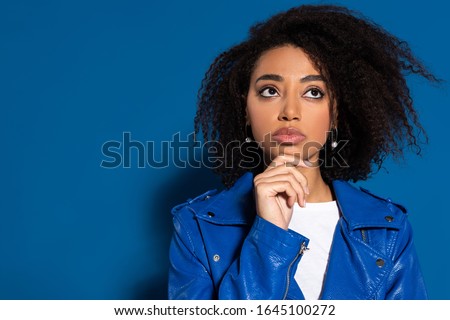 pensive african american woman looking away on blue background