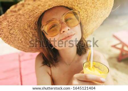 Picture of happy cheerful and satisfied young woman look on camera through yellow sunglasses. Enjoy summertime on beach. Alone travel abroad to rest on paradise island
