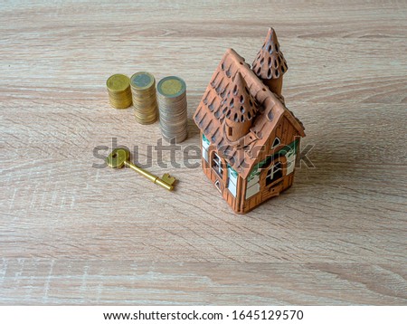 Model of a house, Stack of European Euro coins and golden key On Wooden Table. Real estate agency, mortgage loan, lottery, buying property.Home loan and investment concept. Copy space