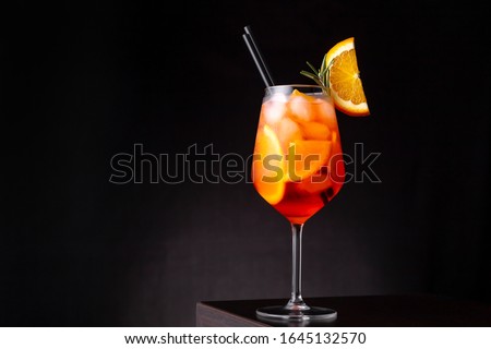 Glass of ice cold Aperol spritz cocktail served in a wine glass, decorated with slices of orange and rosemary branch, placed on a bar counter Royalty-Free Stock Photo #1645132570