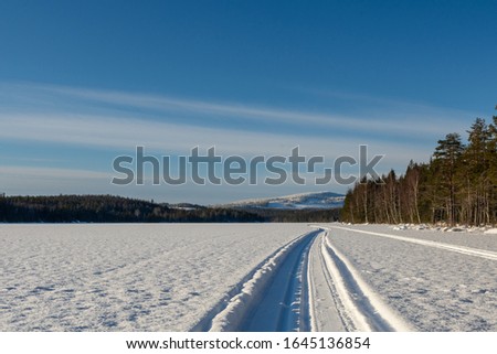 Prepared ski track on a lake with snow covered forest up in the mountain in background, picture from Mellansel Vasternorrland, Sweden.