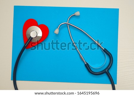 Red heart and stethoscope on a blue paper background. Health care concept, health worker, heart health care, medical care. Flat layout, top view.
