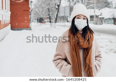 A woman on the street in winter protects the respiratory tract from the epidemic of coronavirus. Protection against urban smog and dust