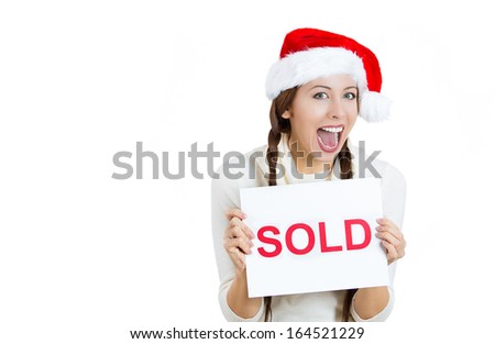 Closeup portrait of excited, happy, smiling young woman in red santa claus hat holding a sold sign with hands, isolated on white background with copy space. Positive human emotions, facial expressions