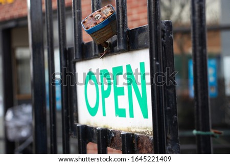 A sign saying "open" on a iron gate