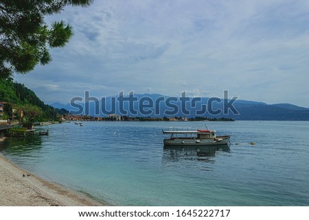 The shore of lake Garda. A boat. Toscolano Maderno embankment in the background. Italy. Soft focus, blurry background.