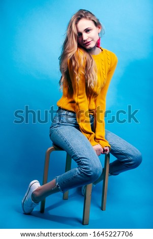 young pretty teenage modern hipster girl posing emotional happy on blue background, lifestyle people concept