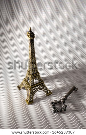 Vintage Property Key and an Eiffel Tower Miniature isolated on a White Background