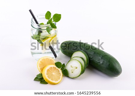 
sliced ​​lemon with whole cucumber and slices with mint leaves on white background, refreshing drink in glass jar with lemon and cucumber with sorbet