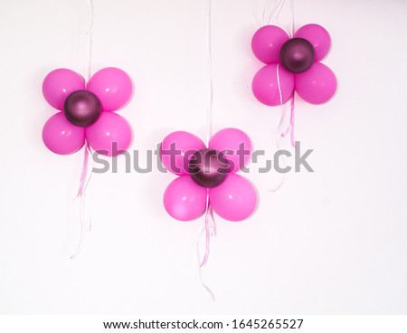 pink and red balloons decor, like three flowers on a white wall