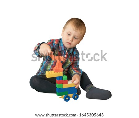 Little serious cute boy plays with colorful blocks at home, builds a car. Isolated photo