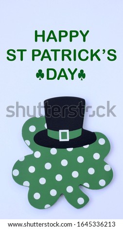 wooden crafted green with white polka dot four leaf clover with black leprechaun hat on a white background with st patricks day message