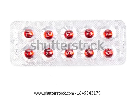 Medications: red round tablets in a silver blister isolated on white background. Macro close up