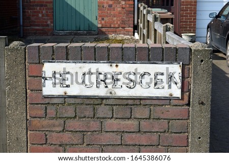 Broken Metal Street Sign 'The Crescent' on Brick Wall 