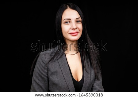 Portrait of young business woman in a grey jacket on black background.