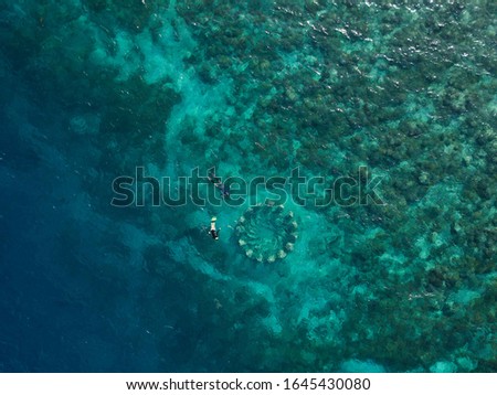 This Gili Meno dive site is one of the most popular sites in the Gili Islands of Indonesia and is made up for 48 life sized sculptures. This is an aerial photo of two snorkelers exploring the site. 