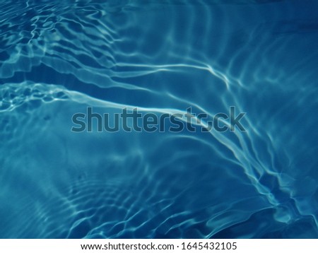 The​ abstract​ of surface​ blue​ water​ in​ the​ swimming​ pool​ reflected​ with​ sunlight​ for​ background​