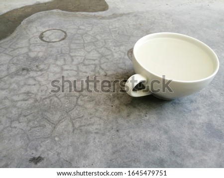 The white​ cup​ on the​ floor​ concreat​ background. Rust​ of​ surface​ wall​ concrete​ for​ background​