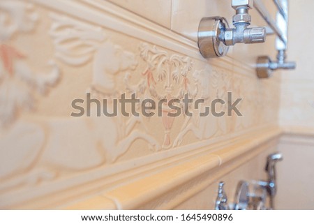 Expensive Square beige tiles in the bathroom and toilet with a vintage floral pattern.