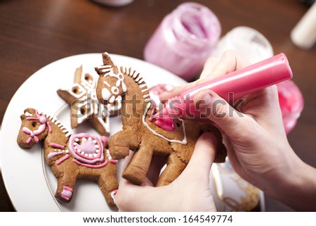 Close-up of hands with gingerbread cookie and pipping bag Royalty-Free Stock Photo #164549774