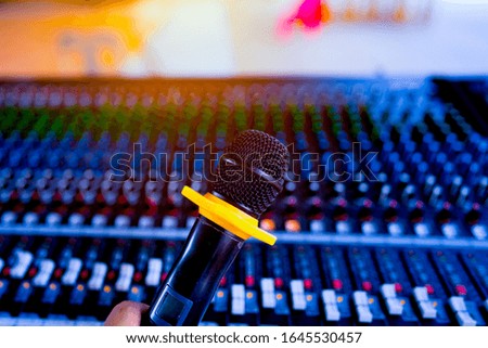 Blurred microphone on and sound mixing console control blurred background