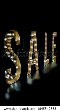 Big standing letter sale sign with lights on a dark background