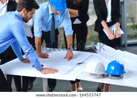 business people group on meeting and presentation  in bright modern office with construction engineer architect and worker looking building model and blueprint planbleprint plans Royalty-Free Stock Photo #164555747