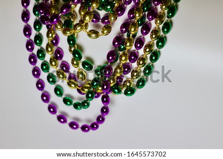 Close up abstract view of traditional three color (green, gold, and purple) Mardi Gras bead necklaces on white background