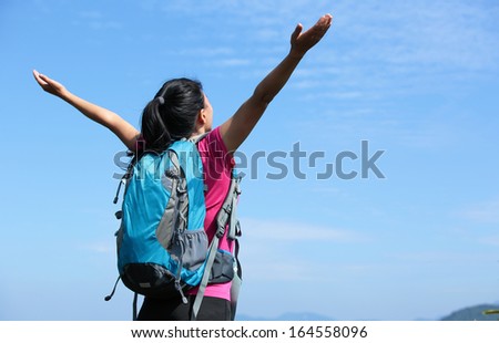 hiking woman with her arms raised on mountain peak