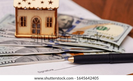 Handle for signing a document on the sale and purchase of a house. Model of the house near the money and the document on the purchase of housing