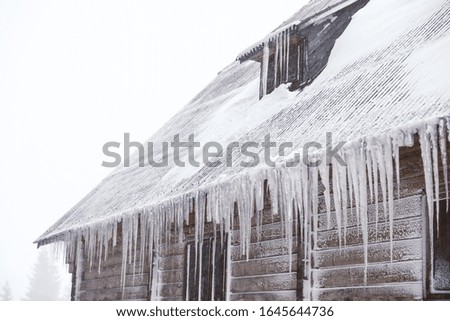 Wooden house with icicles on snowy day. Winter vacation