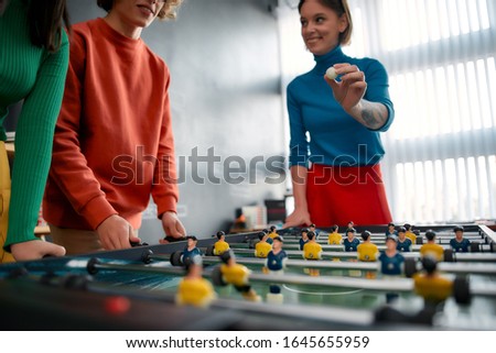 Group of young and happy web designers in casual wear playing table soccer in the creative office. Young cheerful woman holding table football ball and smiling. Office activities. Happy employees Royalty-Free Stock Photo #1645655959