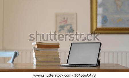 Close up view of simple workplace with mock up digital tablet and books on wooden desk in living room