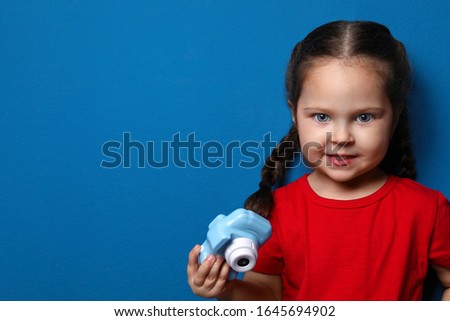 Little photographer with toy camera on blue background. Space for text