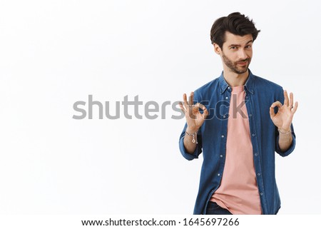 Guy knows how make perfection. Confident good-looking charming bearded man showing okay, ok signs and smirk as arranging best new year party ever, encourage everything be great, white background
